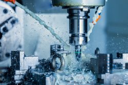 A process of vertical cnc steel milling with external water coolant streams, splashes and a lot of metal chips. Fast shutter speed for motion freezing.